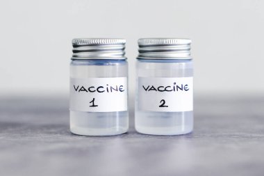 covid-19 aşı yarışı ve salgına karşı bağışıklık, Aşı 1 ve Aşı 2 etiketli ampuller birinci ve ikinci aşıyı ya da farklı aşı seçeneklerini etiher 'a atıfta bulunarak
