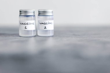 covid-19 aşı yarışı ve salgına karşı bağışıklık, Aşı 1 ve Aşı 2 etiketli ampuller birinci ve ikinci aşıyı ya da farklı aşı seçeneklerini etiher 'a atıfta bulunarak