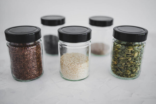 simple food ingredients concept, seed jars with sesame poppy pupmkin chia and flax seeds as important nutrient sources for nutrition shot on white background