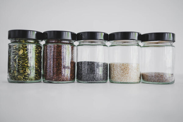 simple food ingredients concept, seed jars with sesame poppy pupmkin chia and flax seeds as important nutrient sources for nutrition shot on white background