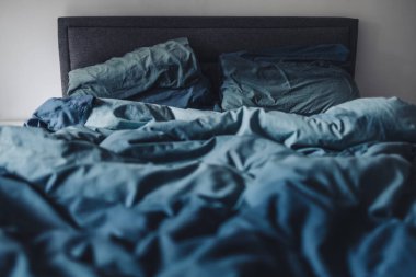 dağınık kraliçe yatağı mavi yorgan örtüsü ve buruşuk çarşaflar, uyku konsepti ya da çift hayatı