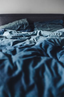 dağınık kraliçe yatağı mavi yorgan örtüsü ve buruşuk çarşaflar, uyku konsepti ya da çift hayatı
