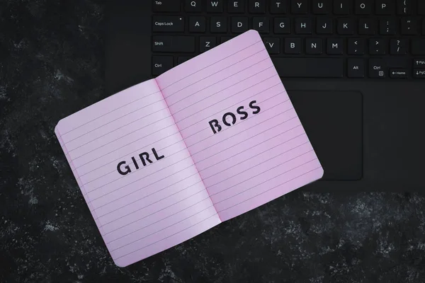 equal opportunities concept, Girl Boss text on top of pink notebook on laptop keyboard on black background