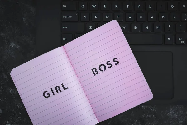 equal opportunities concept, Girl Boss text on top of pink notebook on laptop keyboard on black background