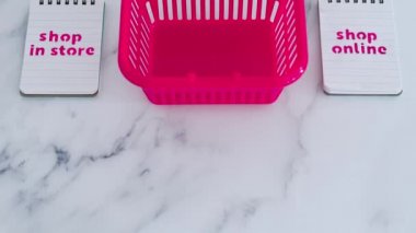  Dükkandaki pembe alışveriş sepetleri not defterleri, rekabet ve perakende sektörü kavramsal imaj üzerine çevrimiçi metinler vs