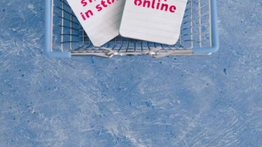 Dükkanda alışveriş sepeti ile mağaza vs mavi arkaplan, rekabet ve perakende sanayi kavramsal görüntü üzerine notlar online metinler