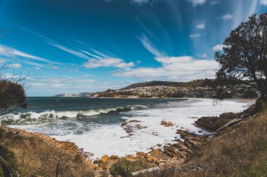 BLACKMANS BAY, TASMANIA - March 6th, 2020: view of the popular Blackmans Bay beach in southern Hobart on a very windy day with intense swell and waves  clipart