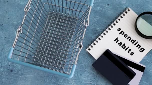 用购物篮 放大镜和付款卡 钱和消费者行为在笔记本上写上消费习惯的文字 — 图库视频影像