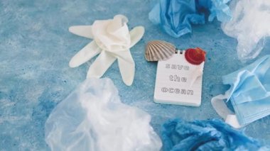 Mavi arkaplan üzerindeki okyanus metnini deniz kabukları ve çevresel kirliliğin düzeltilmesi, ekoloji ve gezegene olan saygının plastik çöp sembolüyle kaydet
