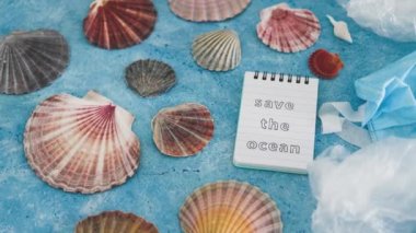 Mavi arkaplan üzerindeki okyanus metnini deniz kabukları ve çevresel kirliliğin düzeltilmesi, ekoloji ve gezegene olan saygının plastik çöp sembolüyle kaydet