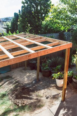 Avustralya 'daki tropikal bitkilerle çevrili güneşli arka bahçedeki ahşap yapılı inşaat bahçesi pergola altında. 