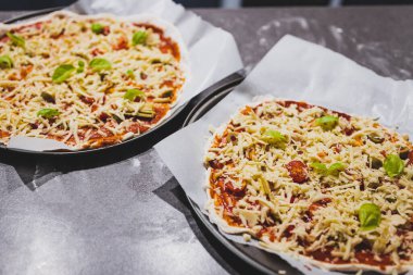 Ev yapımı vejetaryen pizzalar mutfak tezgahında hazırlanıyor, sağlıklı bitki temelli yemek tarifleri.