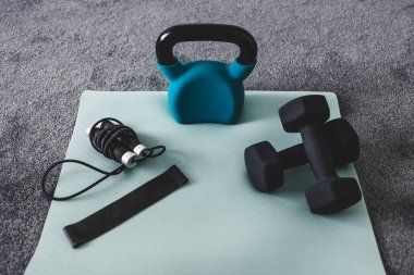 Yoga hasırı ağırlıkları ve ince gri ve mavi tonlu ip atlama da dahil olmak üzere karışık fitness malzemeleriyle ev yapımı spor salonu 