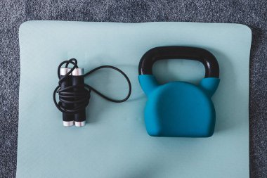 Kettlebell ve yoga minderinde ip atlama, ev jimnastiği konsepti ve ağırlık antrenmanı hafif gri ve mavi tonlarda kardiyo fitness stili. 