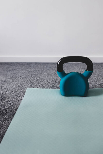 домашний тренажерный зал со смешанными предметами фитнеса, включая коврик для йоги и гири с тонкими серыми и синими тонами 