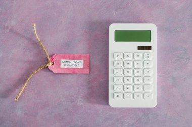 Pembe masasında hesap makinesi olan kadınlara ait iş etiketi, eşitliği ve eşit fırsatları destekliyor