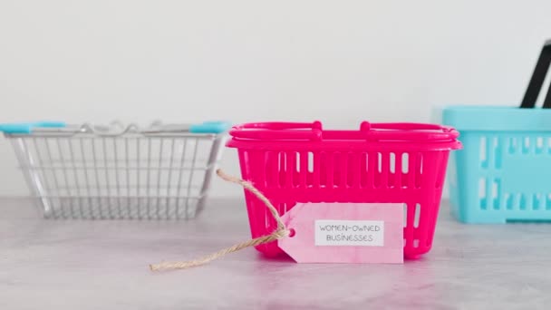Женщины Владеют Бизнесом Ярлык Розовой Корзиной Покупок Среди Конкурентов Синих — стоковое видео