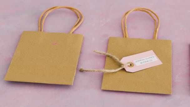 競合他社のバッグに囲まれたショッピングバッグに女性が所有するビジネスタグ — ストック動画