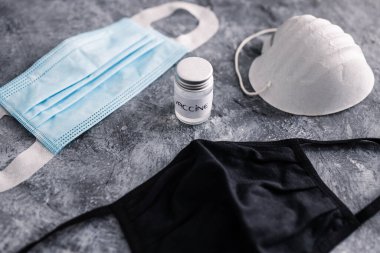 Aşı ampulü farklı türde maske, covid-19 aşı ırkı ve salgına karşı bağışıklık sistemiyle çevrili.