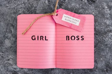 Pembe not defterinde kız patrona ait iş etiketi var. Eşitliği ve eşit fırsatları destekliyor.