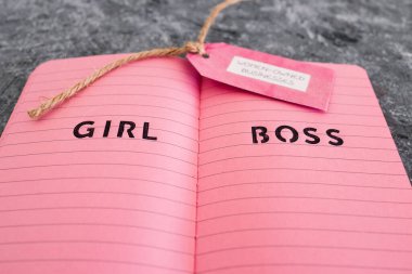 Pembe not defterinde kız patrona ait iş etiketi var. Eşitliği ve eşit fırsatları destekliyor.