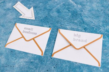 Küçük işletmeler, büyük markalara karşı haber bülteni e-posta zarfları üzerinde küçük olanı işaret eden, müşteri davranışı kavramını ve küçük yerel işletmeleri destekleyen ok işaretli büyük markalara karşı.