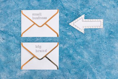 Küçük işletmeler, büyük markalara karşı haber bülteni e-posta zarfları üzerinde küçük olanı işaret eden, müşteri davranışı kavramını ve küçük yerel işletmeleri destekleyen ok işaretli büyük markalara karşı.