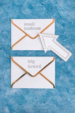 Küçük işletmeler, büyük markalara karşı haber bülteni e-posta zarfları üzerinde küçük olanı işaret eden, müşteri davranışı kavramını ve küçük yerel işletmeleri destekleyen ok işaretli büyük markalara karşı.