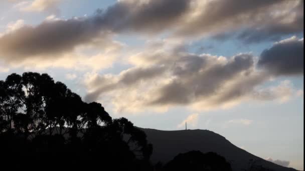 澳大利亚塔斯马尼亚的冬季 乌云在山上翻滚 金色的落日声闪耀在茂密的植被之上 — 图库视频影像