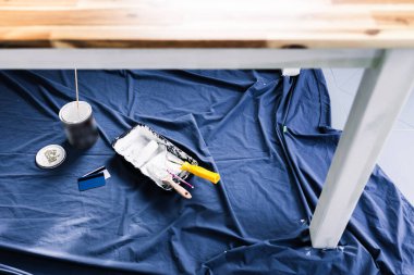 Boya tepsisi silindirli beyaz boya ve mavi dökümlü ödeme kartıyla fırçalar. Renklendirme ve yenileme masrafları, sığ bir alanda boya kutusuyla çekilen bulanık yazı.