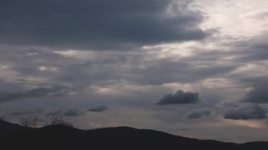 Gün batımının zaman çizelgesi karanlığa dönüşüyor ve bulutlar dağların üzerinde yuvarlanıyor ve kışın Tazmanya, Avustralya 'da yoğun bitki örtüsü vuruyor.