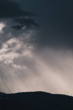 Kışın Tazmanya, Avustralya 'da yoğun güneş ışınları ile dağların üzerinde yoğun fırtınalı bulutlar oluşur.