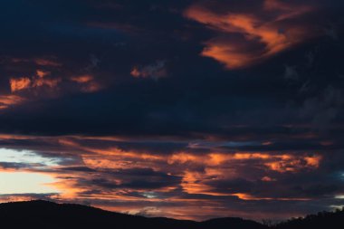 Tazmanya, Avustralya 'da kışın çekilen pembe ve turuncu bulutlarla gün batımı gökyüzü