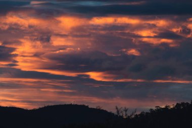 Tazmanya, Avustralya 'da kışın çekilen pembe ve turuncu bulutlarla gün batımı gökyüzü