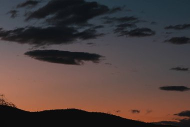 Tazmanya, Avustralya 'da kışın çekilen dağların üzerinde mor ve turuncu renkte günbatımı gökyüzü