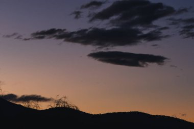 Tazmanya, Avustralya 'da kışın çekilen dağların üzerinde mor ve turuncu renkte günbatımı gökyüzü