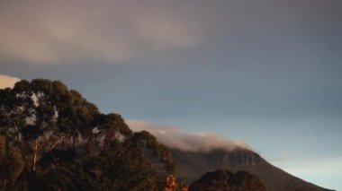 timelapse of dusk and sunset with clouds over the mountains with eucalyptus gum trees in the foreground shot in Tasmania, Australia in winter