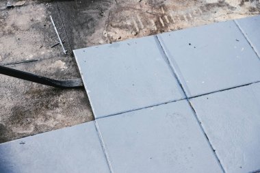Altında beton döşeme, yıkım ya da yenileme ve ev tadilatı kavramını ortaya çıkarmak için mavi karolar yırtılıyor.