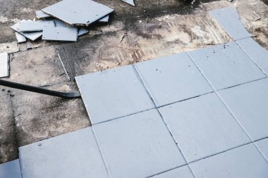 Altında beton döşeme, yıkım ya da yenileme ve ev tadilatı kavramını ortaya çıkarmak için mavi karolar yırtılıyor.