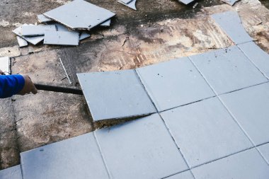 Altında beton döşeme, yıkım ya da yenileme ve ev tadilatı kavramını ortaya çıkarmak için mavi karolar yırtılıyor.