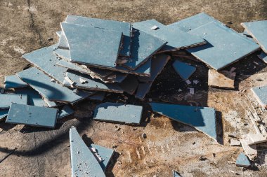 Altında beton döşeme, yıkım ya da yenileme ve ev tadilatı kavramını ortaya çıkarmak için mavi karolar yırtılıyor.