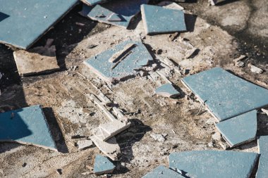 Altında beton döşeme, yıkım ya da yenileme ve ev tadilatı kavramını ortaya çıkarmak için mavi karolar yırtılıyor.