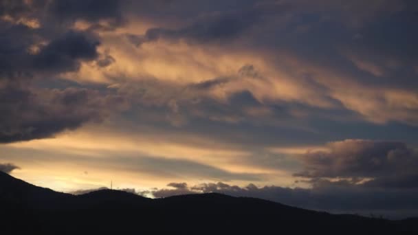 冬にオーストラリアのタスマニアで撮影された山と厚い植生の上を転がる夕暮れと雲に変わる黄金の夕日の経過 — ストック動画