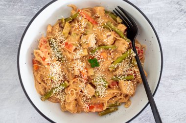 Fıstık ezmesi soslu vegan Thai stiry kızartması ve susam tohumlu vermicelli şehriye, sağlıklı bitki temelli yemek tarifleri.