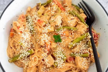 Fıstık ezmesi soslu vegan Thai stiry kızartması ve susam tohumlu vermicelli şehriye, sağlıklı bitki temelli yemek tarifleri.