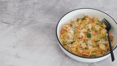 Fıstık ezmesi soslu vegan Thai stiry kızartması ve susam tohumlu vermicelli şehriye, sağlıklı bitki temelli yemek tarifleri.