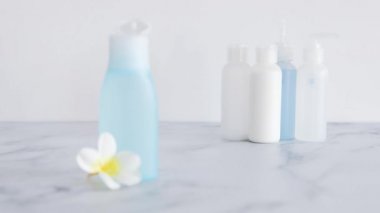 Düşük toksikoloji ve toksik olmayan doğal güzellik ürünleri kavramsal görüntü, el ön plandaki mavi losyon şişesinin önüne bir çiçek yerleştiriyor.  