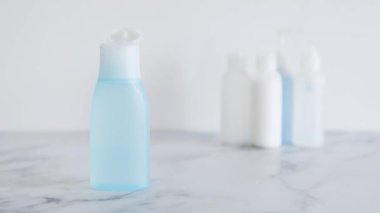 Düşük toksikoloji ve toksik olmayan doğal güzellik ürünleri kavramsal görüntü, ön planda mavi losyon şişesi diğer şişelerden öne çıkıyor  