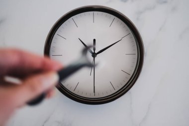 Büyük saatin önünde el ele tutuşan anahtar sığ alan derinliği, verimlilik ve zaman yönetimi metaforu.