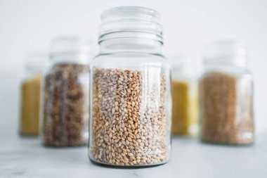 İçinde kinoa pirinç karabuğday kuskusu ve arpa da dahil olmak üzere içinde farklı tahıl türleri bulunan temiz kiler kavanozları, basit doğal sağlıklı bileşenler kavramı.